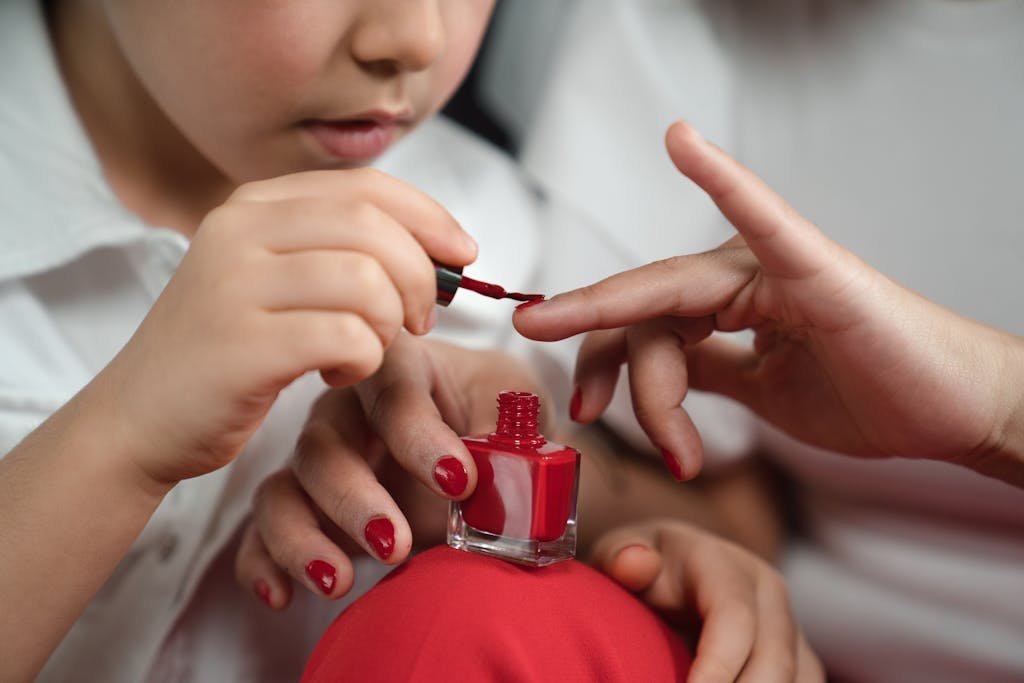 Photograph of a Kid Painting a Person's Fingernails